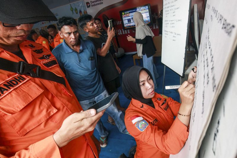 Relatives of affected passengers look on as a National Search and Rescue Agency (Basarnas) officer writes updates on a whiteboard amid ongoing rescue operations on the stricken Virgo Transport 8 ferry on Sunday.